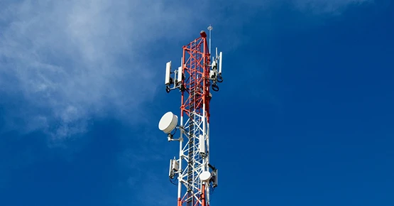 Un ciel bleu avec une antenne télécom télécommunication rouge et blanc au centre