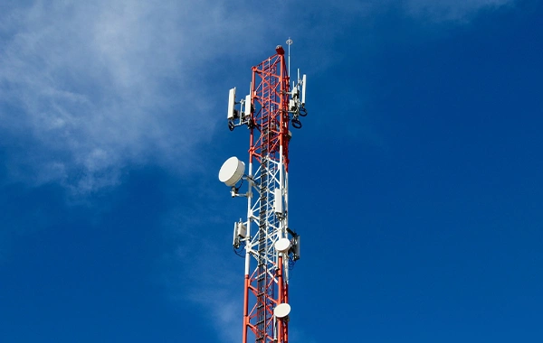 Un ciel bleu avec une antenne télécom télécommunication rouge et blanc au centre