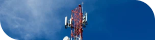 Visuel d'une antenne de télécoms rouge et blanche prise en contre-plongée devant un ciel bleu clairsemé d'un nuage dissipé