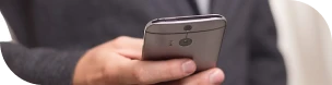 Visuel de la main droite d'un homme en costume tenant un smartphone